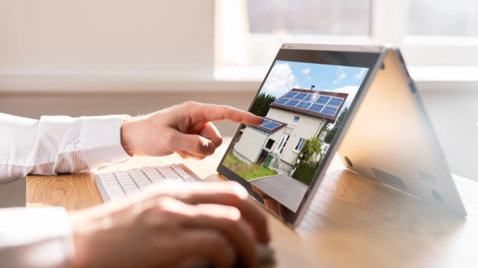 Person reviewing a digital image of a property with solar panels, focusing on professional real estate photography for listings.