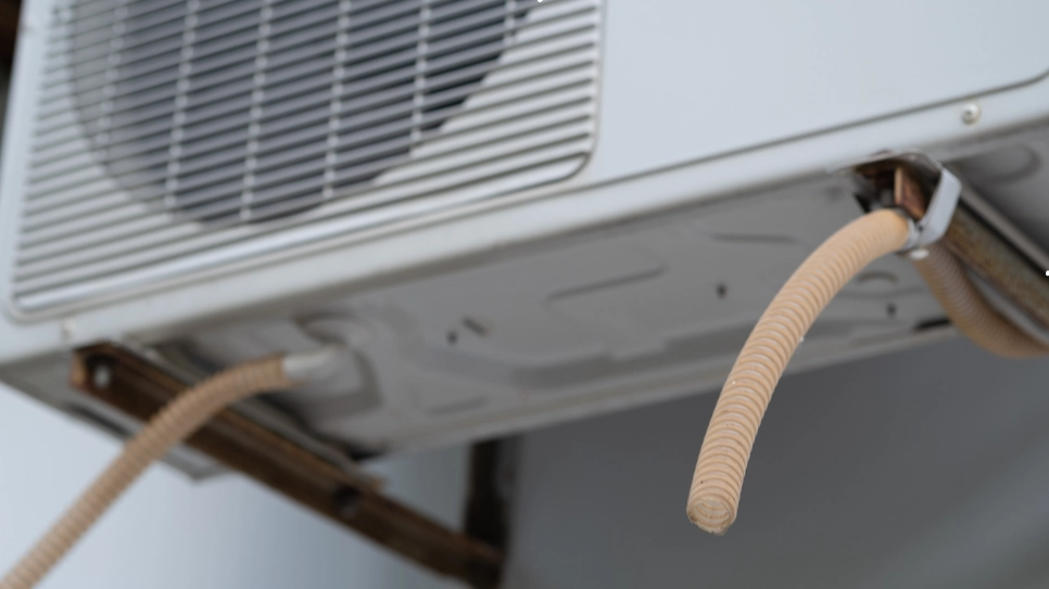 Close-up of an air conditioning unit with visible drain pipes, highlighting proper drainage system installation.