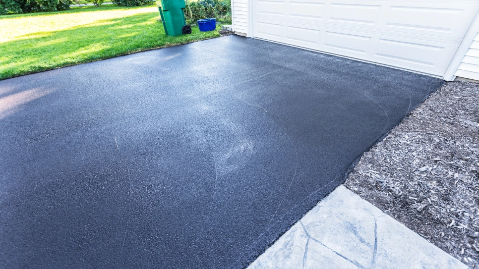 Smooth, newly paved asphalt driveway leading to a garage, showcasing a clean and even surface finish.