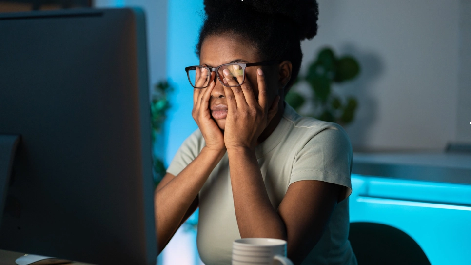 A woman experiencing fatigue and stress during late hours, emphasizing the importance of recognizing and addressing burnout before it escalates.