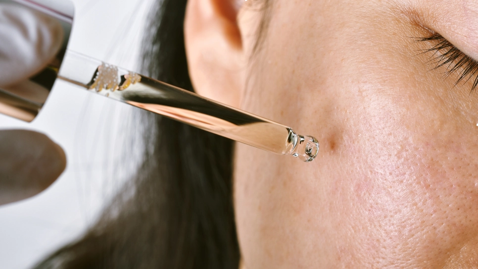 Close-up of serum being applied to cheek, aiming to boost collagen production and improve skin texture.