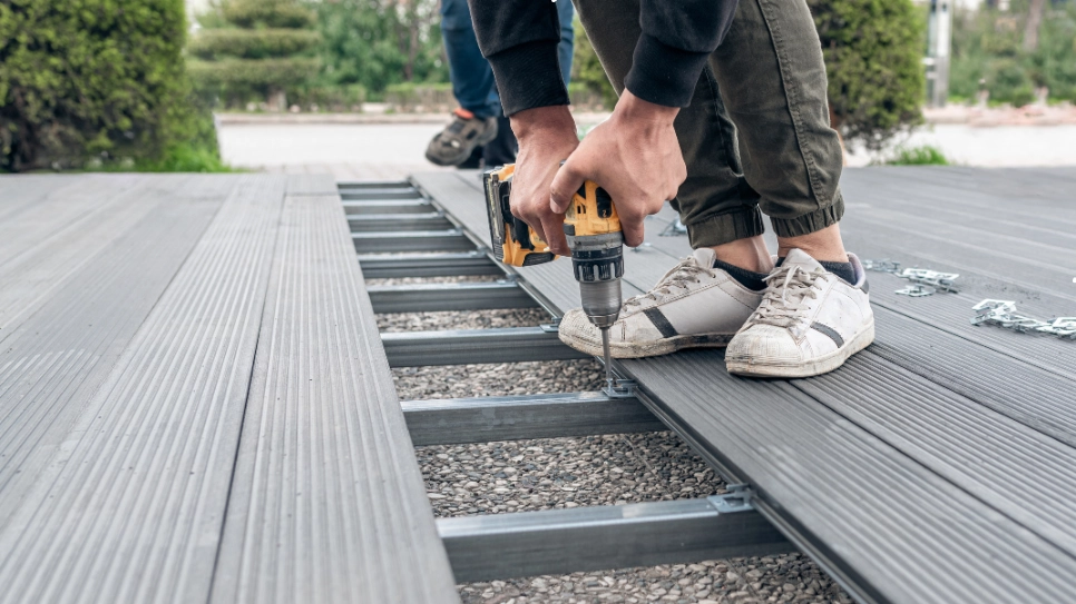 Close-up of composite decking boards being installed with a drill, showcasing durable and low-maintenance materials.