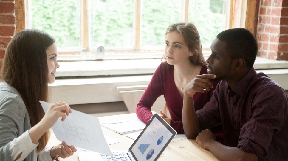 Multiracial couple at real estate agent deciding between building or buying new house.