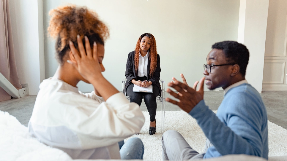 A couple engaging in a conflict resolution counseling session with a therapist, addressing communication issues and relationship challenges.