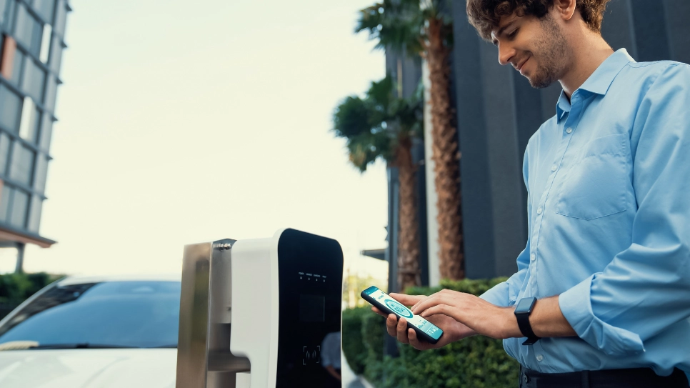 A young man using a smart ev charge app to charge his car.