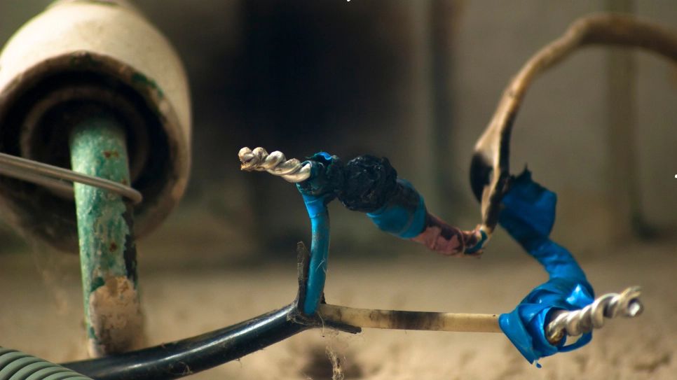 Close-up of exposed and burnt electrical wiring with makeshift repairs, highlighting risks of improper electrical maintenance.