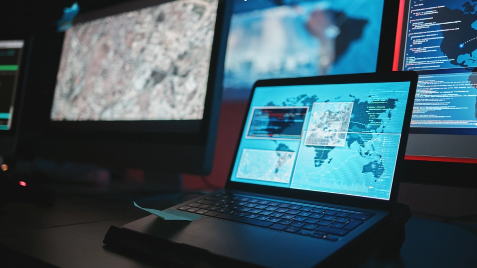 Advanced digital investigation setup displaying global maps and data analysis tools on multiple screens for tracking operations.