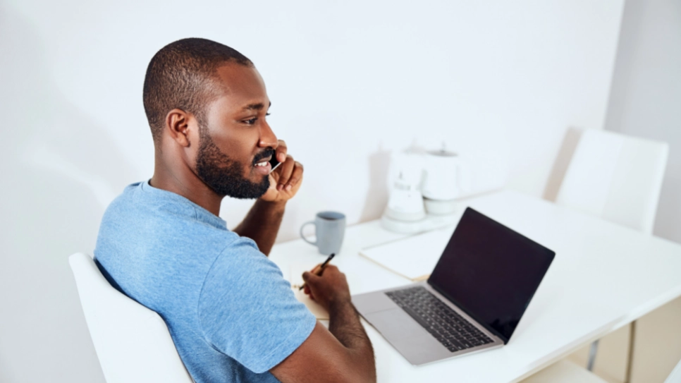 An African man listens to someone on a mobile phone.