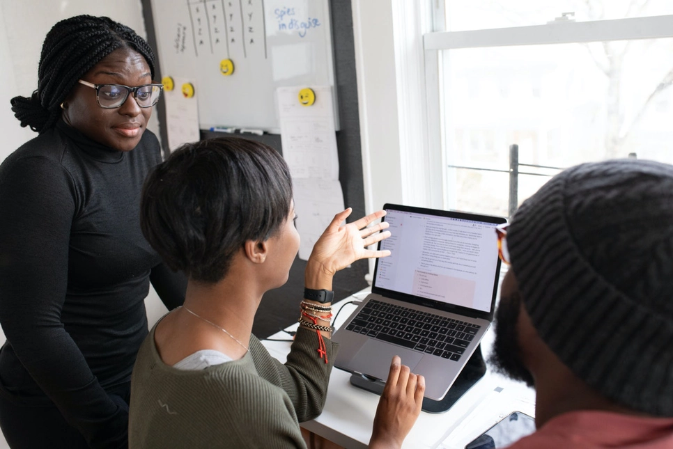 A team of black marketing specialists brainstorming behind a computer.