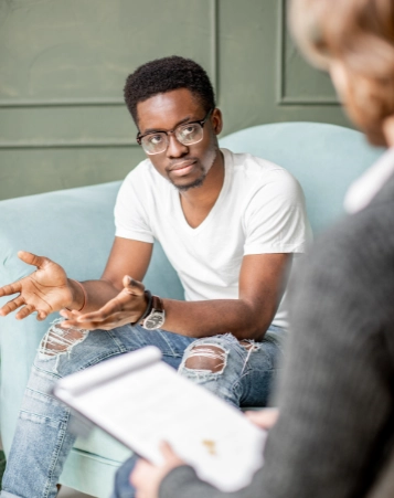 A young man expressing himself during a therapy session, highlighting the value of professional mental health support in a relaxed environment.