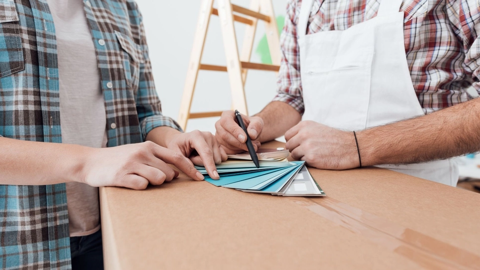 Woman choosing interior house paint with the professional.