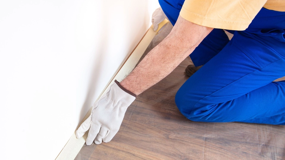 Professional painter preparing room for interior painting with tape.