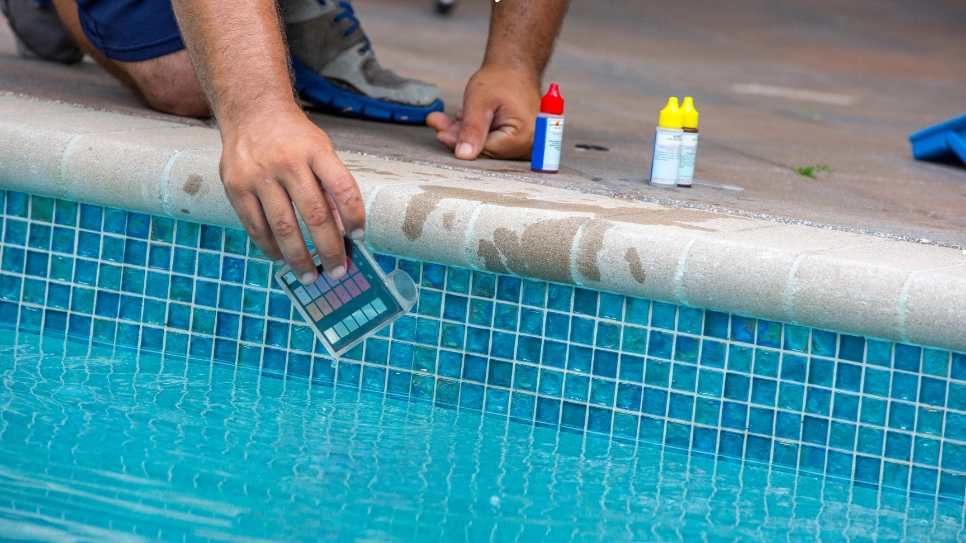 A technician uses a pool testing kit to check water pH and chemical balance for optimal pool maintenance.