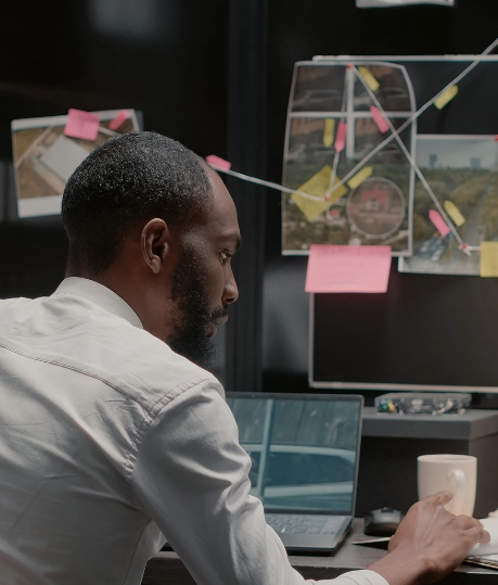 Private investigator at work analyzing case details with pinned evidence, maps, and photographs in an organized office setup.