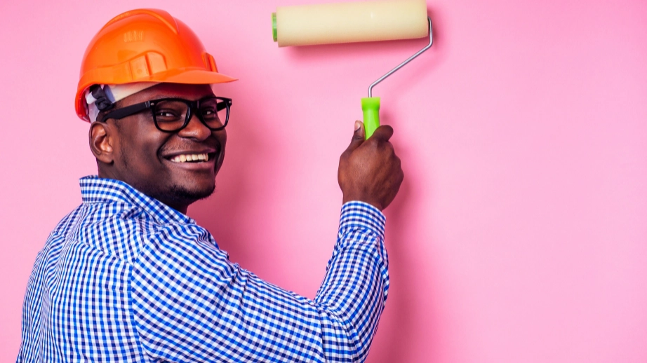 Black South African professional painter, painting a wall pink.