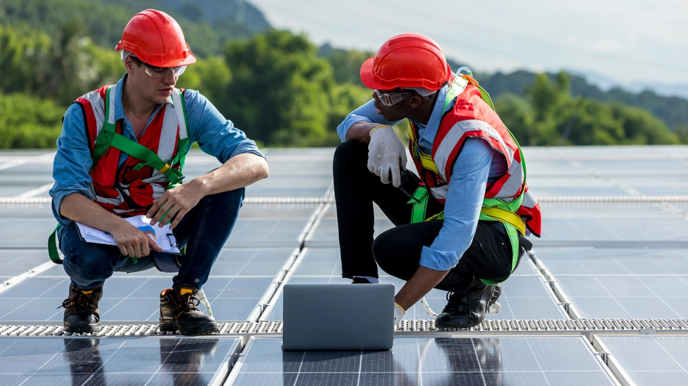 Two South African solar system professionals inspecting photovoltaic panels on the roof.