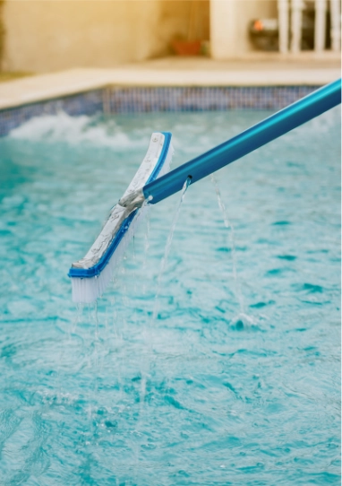 Pool brush cleaning the surface of a swimming pool, illustrating essential maintenance for clear and healthy water.