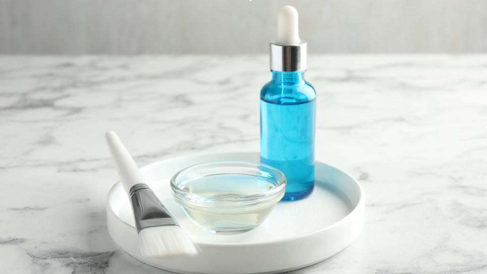 Set of tools for chemical peeling, including a serum bottle, brush, and bowl, prepared for skin rejuvenation treatments.