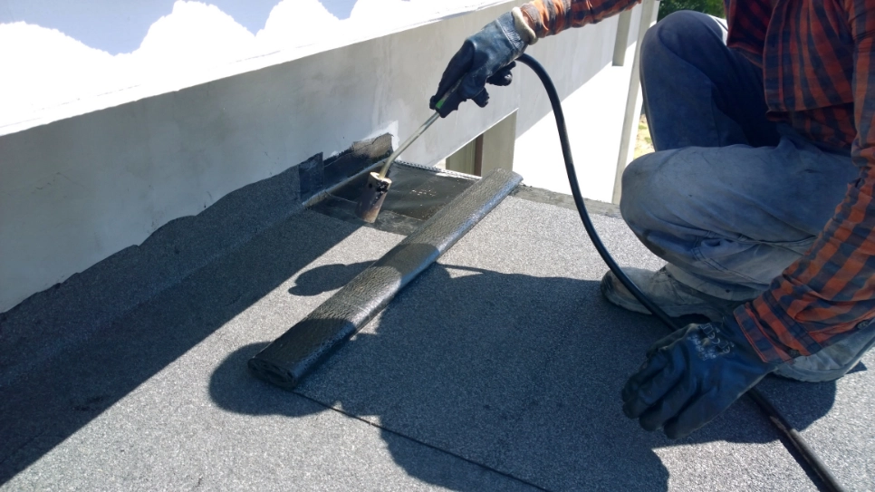 Worker waterproofing the roof using torch.