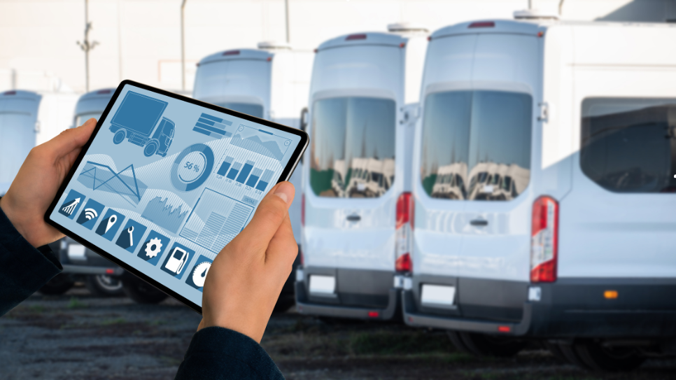 Person holding a tablet showing fleet management analytics in front of parked white commercial vans.