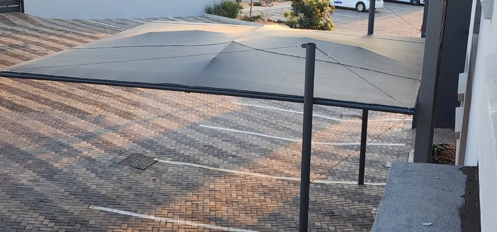 Parking lot shade structure Overhead view of a parking lot with a tensioned shade sail structure, providing sun protection.